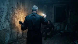 Un exorciste enquêtant dans une pièce sombre pour Unpossess 2, simulation d'exorcisme sur PC.
